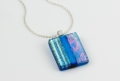 Handmade glass pendant necklace with a clear turquoise base and a mix of subtle dichroic starburst and textured lines, divided by a bold pale blue. Sterling silver 16-18" chain