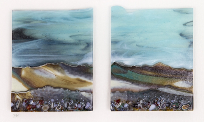 Glass Wall Art, landscape diptych with calm pale blue sky, landscape teal/browns/vanilla headland with a mix of coloured glass frits in foreground.
