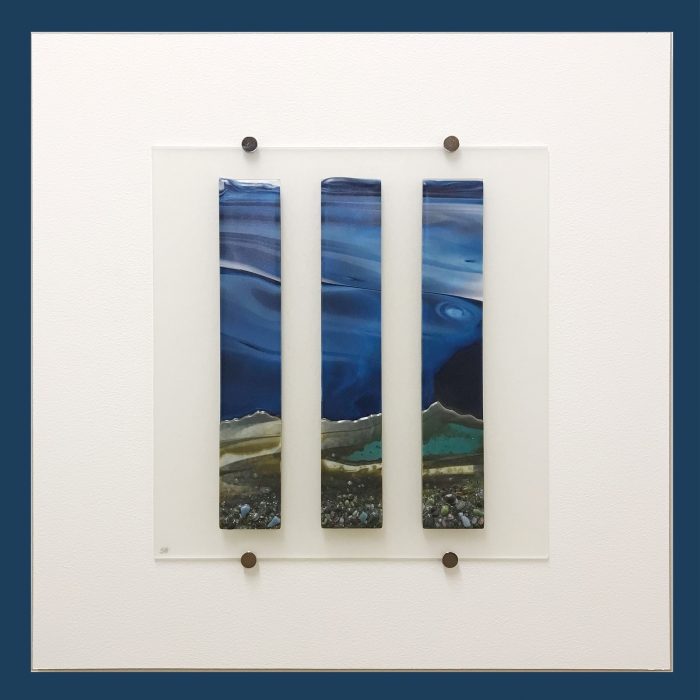Glass Wall Art, coastal landscape triptych with moody blue sky clouds art, landscape greens and cream with glass frits in foreground.