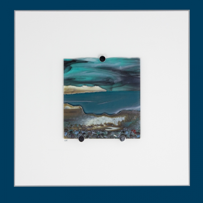 Glass Wall Art, welsh seascape. Aquamarine sky with moody clouds. Steel blue sea. Headland, foreground with french vanilla/browns/teals glass frits to fore. Mounted.