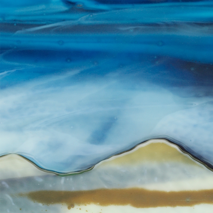 Glass Wall Art, welsh seascape.  Copper blue sky with wispy white clouds. Steel blue sea. Headland, foreground with french vanilla/browns/teals glass frits to fore. Detail.