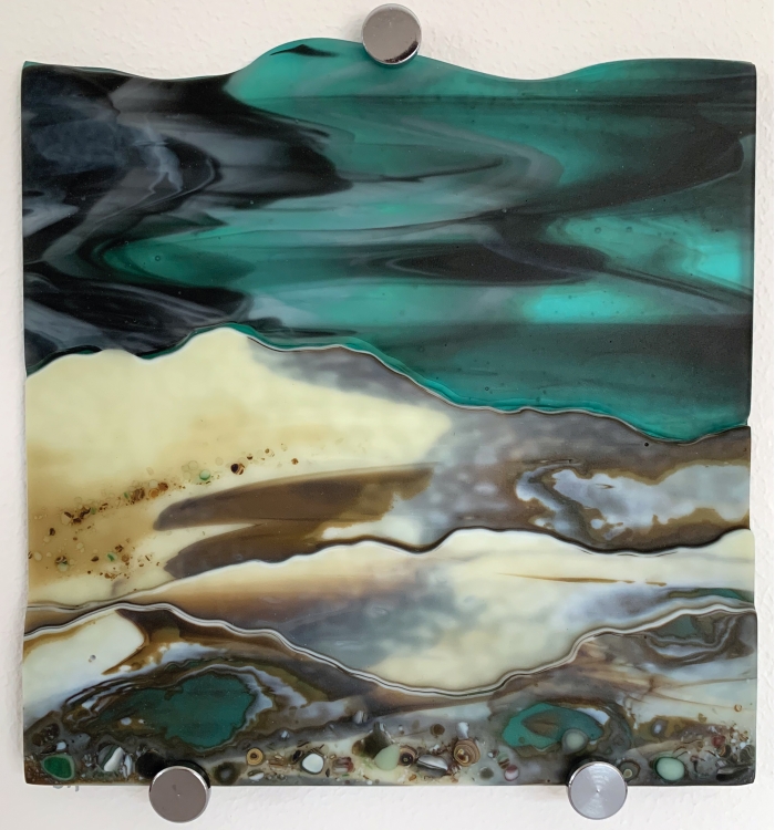 Glass Wall Art, welsh coastline with moody aquamarine sky, vanilla/greens/grey landscape.